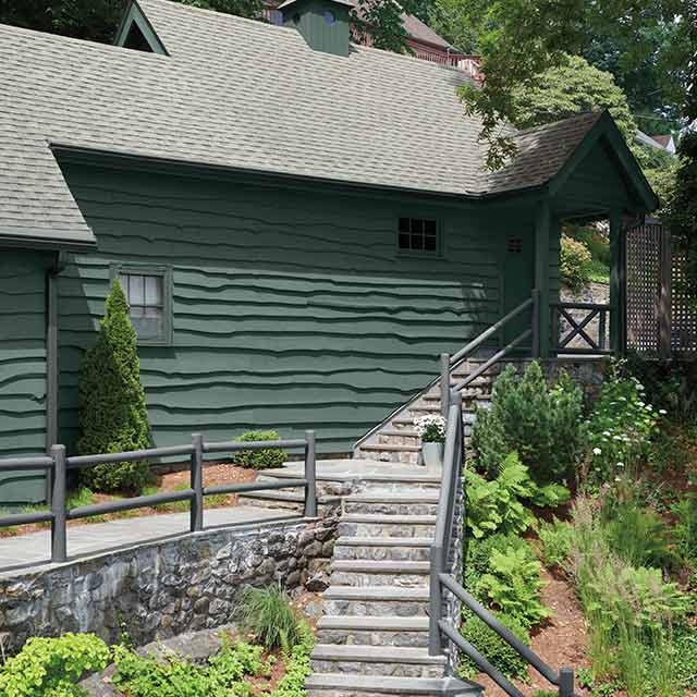 Cabin painted in deep green with gray railing and stone staircase. Cabin painted in deep green with gray railing and stone staircase.