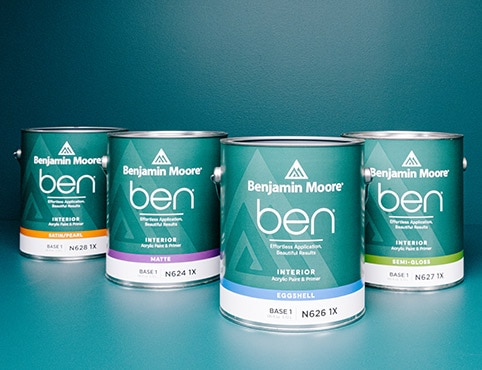 Four gallons of ben Interior paint on a blue table in front of a blue painted wall. Four gallons of ben Interior paint on a blue table in front of a blue painted wall.